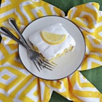 A plate with a slice of lemon cake and two forks on the plate.
