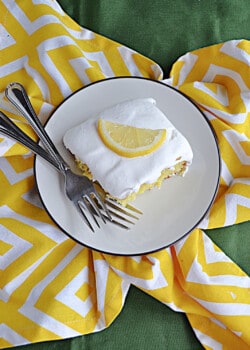 A plate with a slice of lemon cake and two forks on the plate.