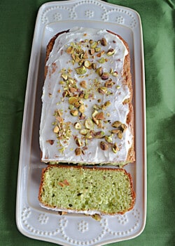 Pistachio Loaf Cake on a platter with a slice cut off of it.