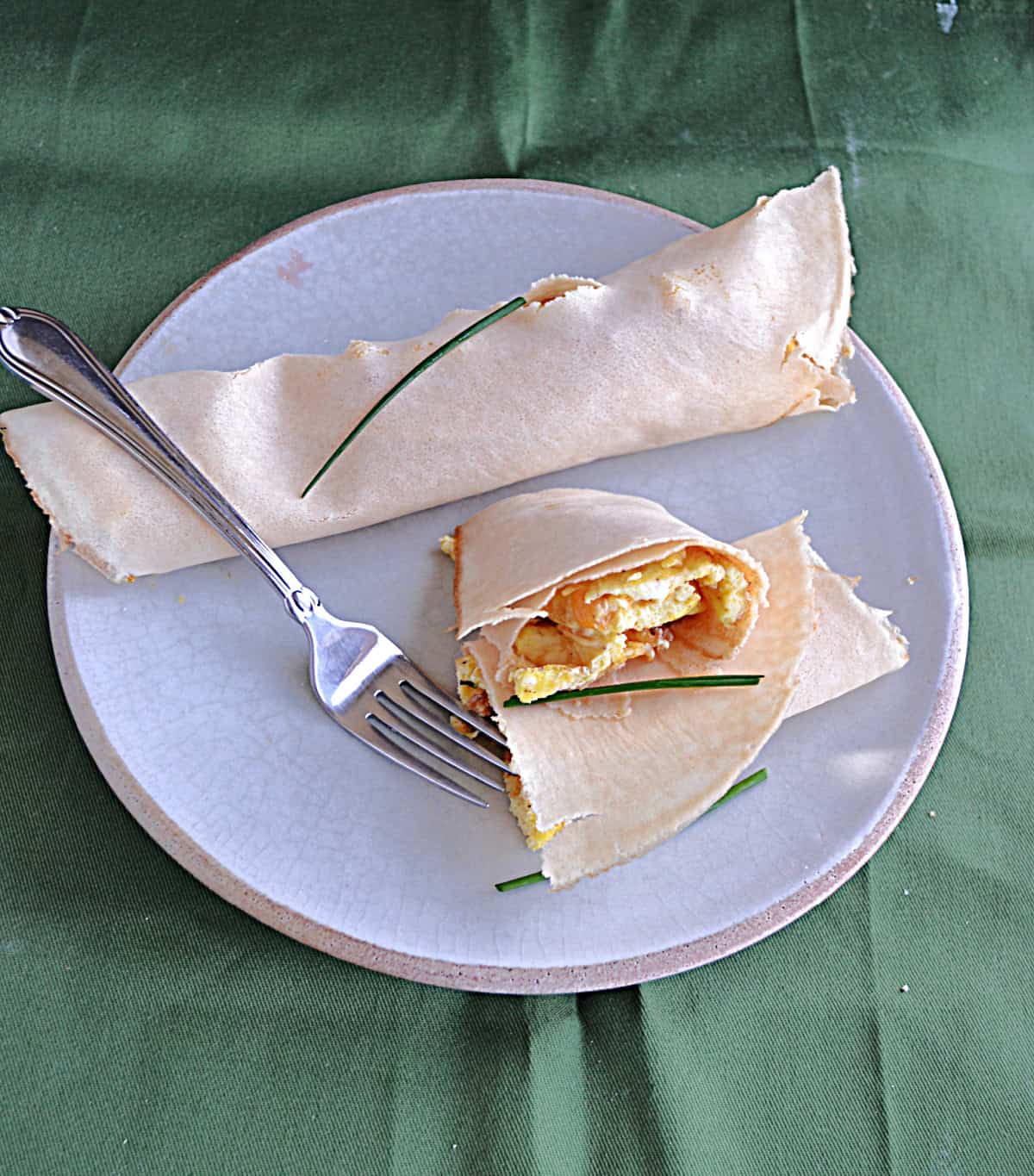 A plate with one whole crepe and one crepe cut in half to show the filling inside.