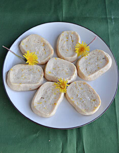 A plate of cookies with dandelions scattered on the plate.