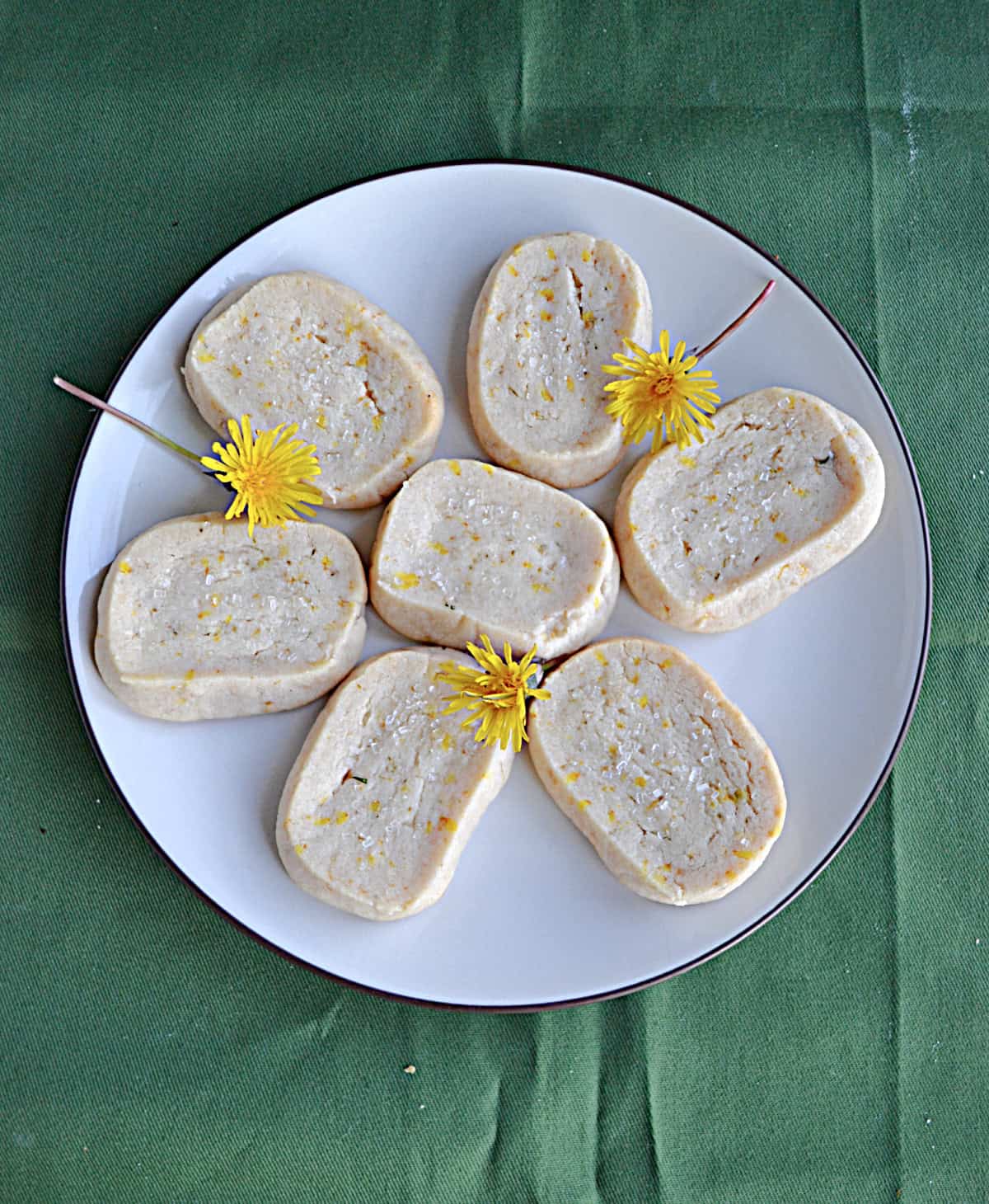 A plate of dandelion cookies with the dandelions on the plate.