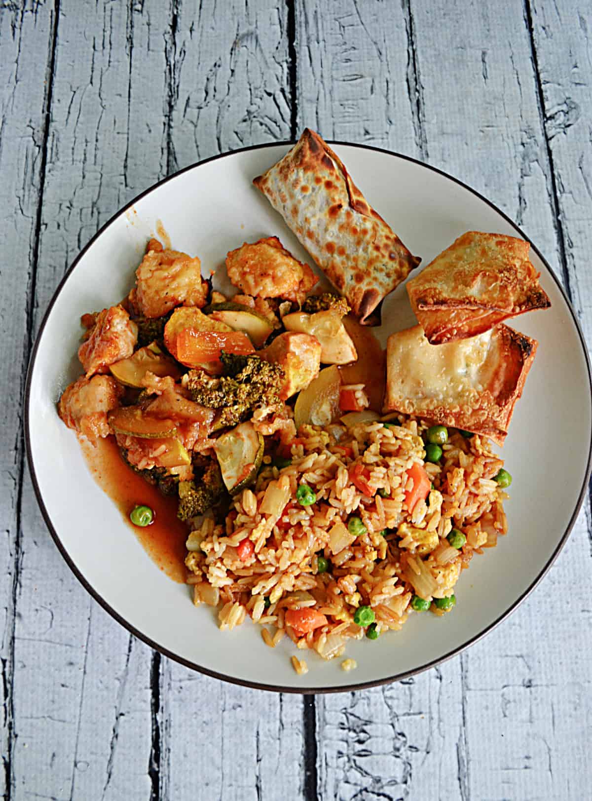 A plate with chicken, fried rice, crab rangoon, and egg roll on it.