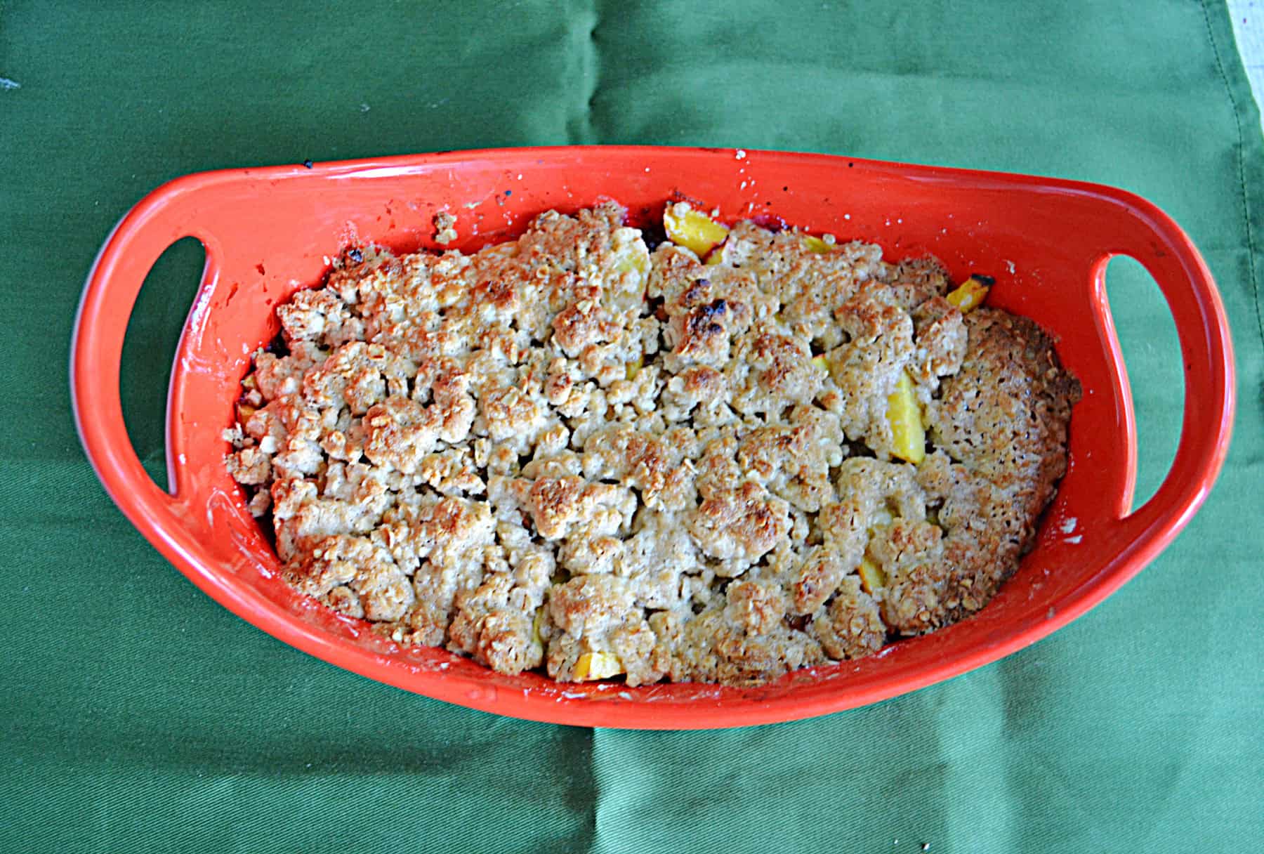 A dish with peach crisp and golden brown topping.