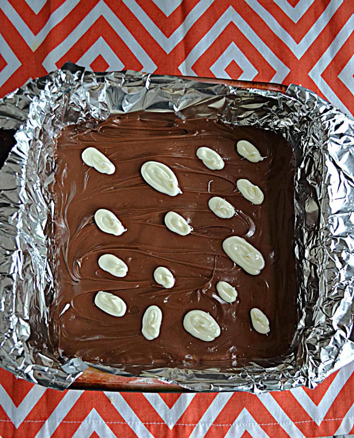 A pan of milk chocolate bark with white chocolate ovals on top.