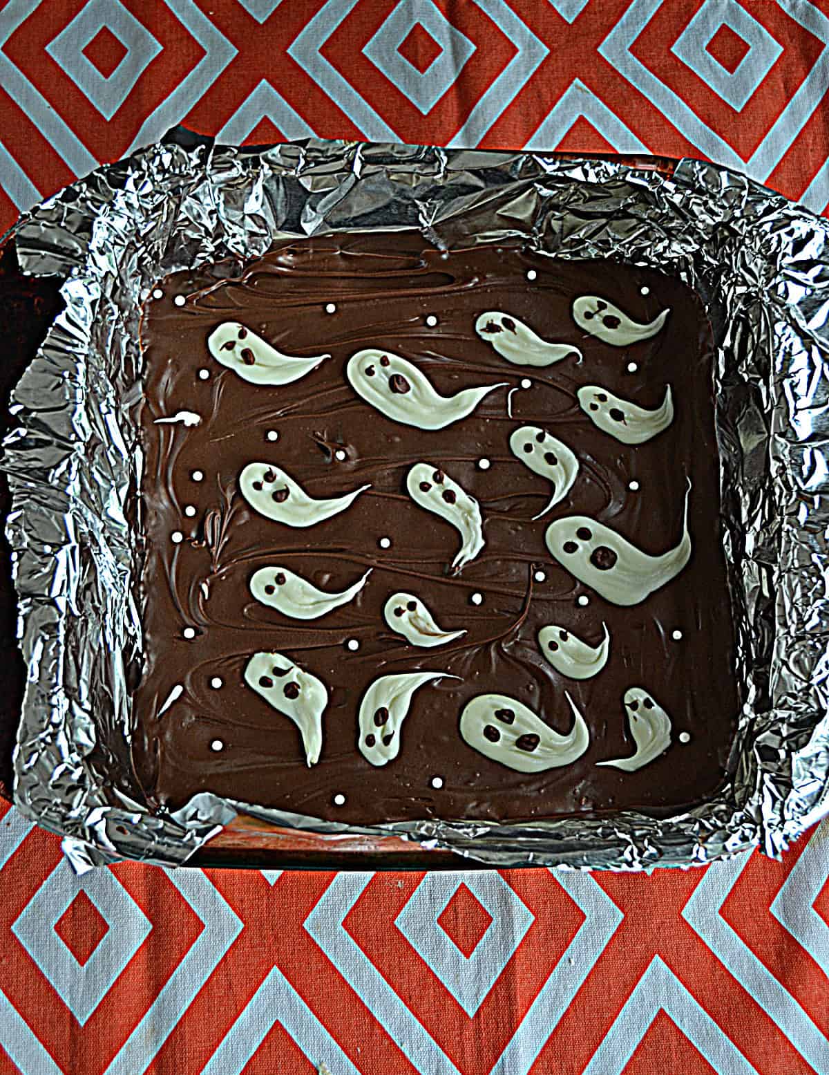 A pan of chocolate bark with white ghosts on top.