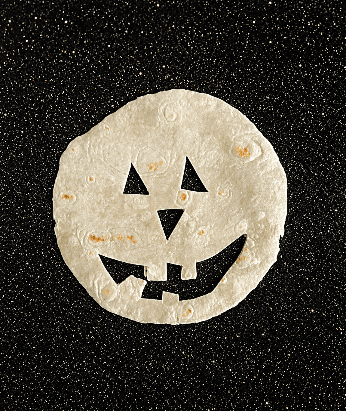 A tortilla with a Jack-o-lantern face cut out of it.