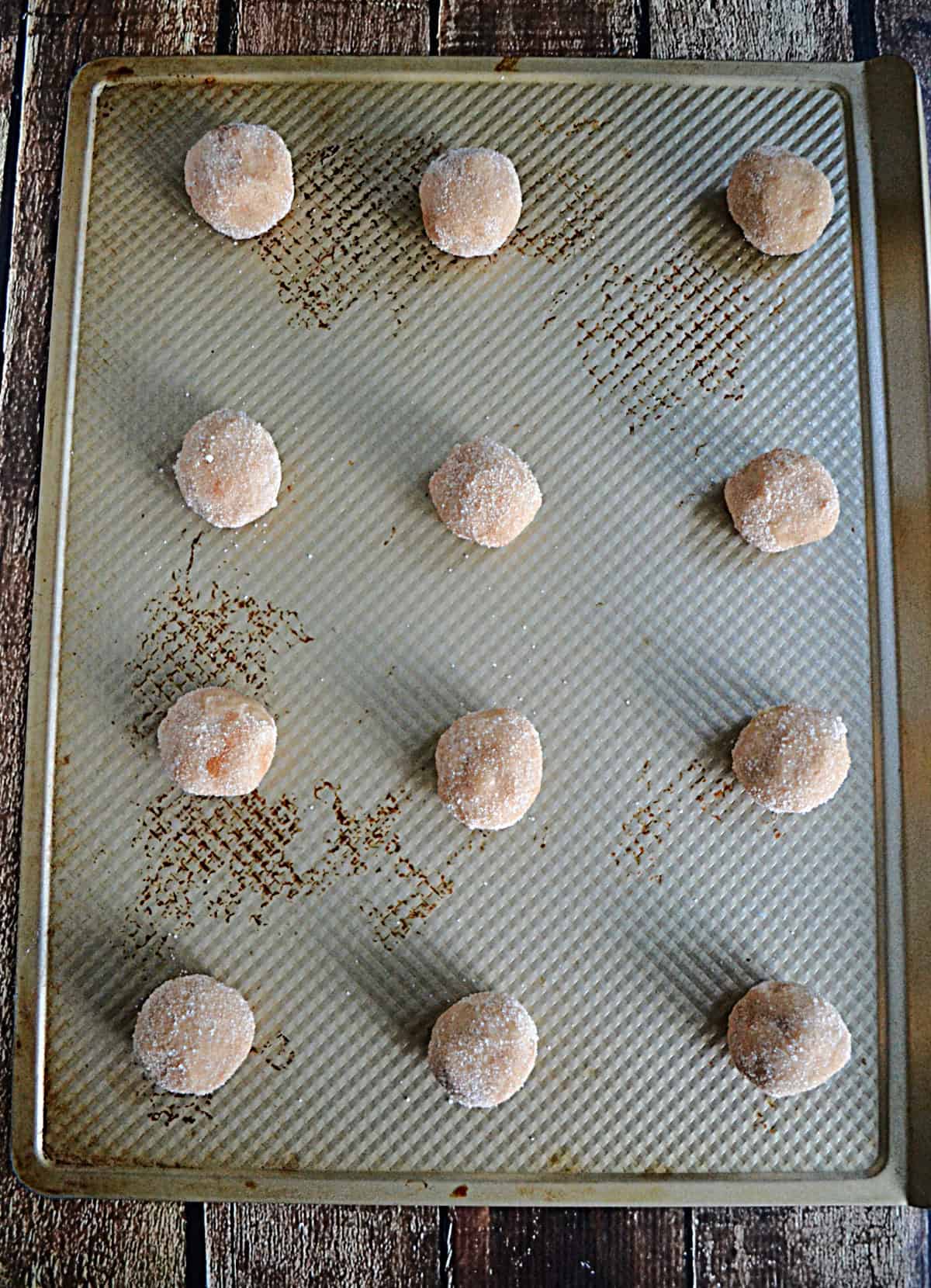 A baking sheet with cookie dough balls on it.
