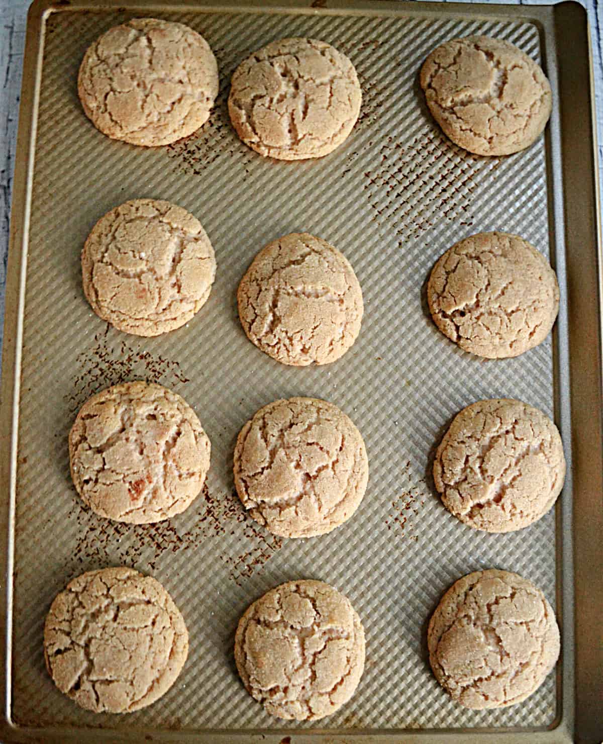 A cookie sheet with baked snickerdoodle cookies on it.