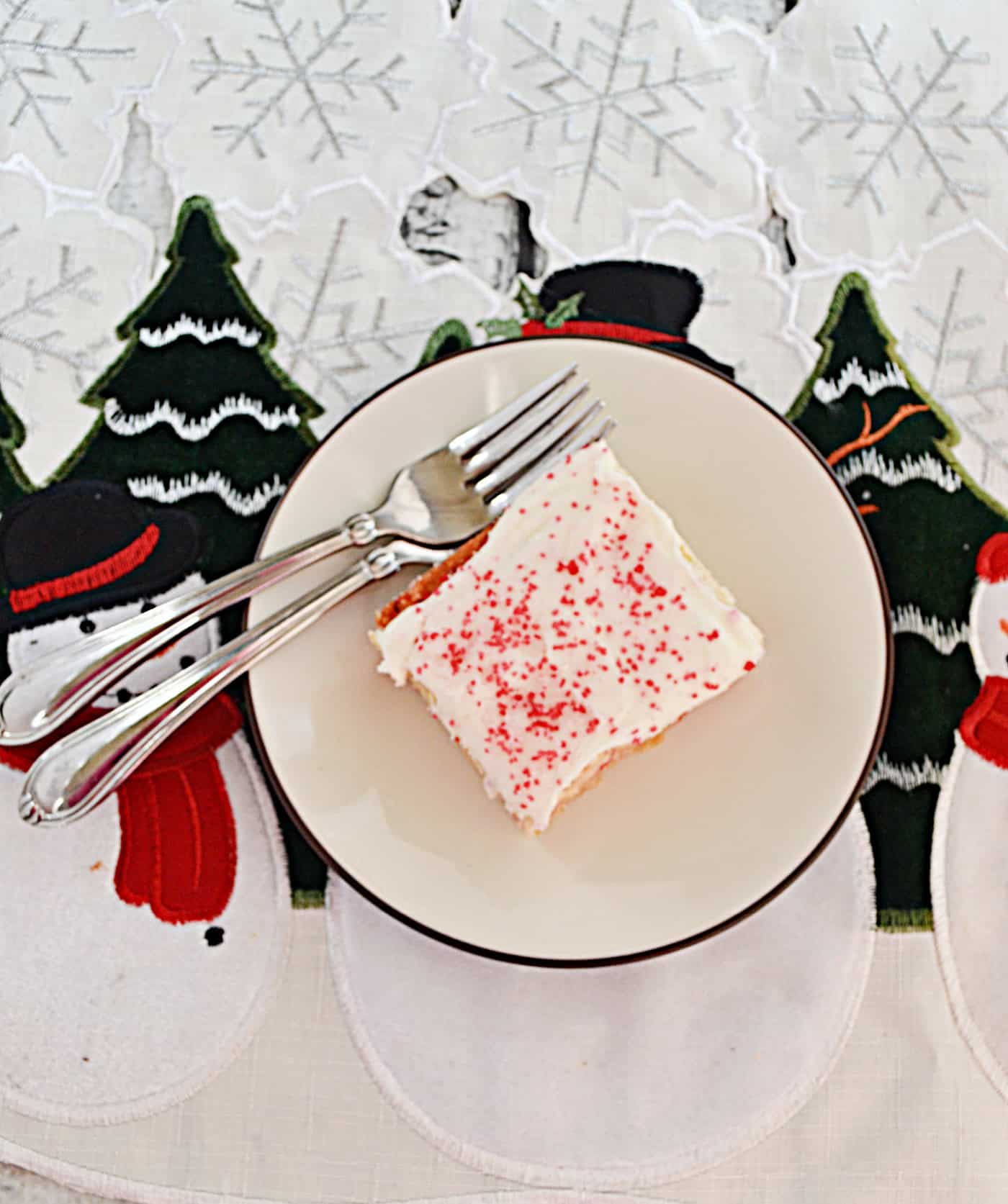 A plate with 2 forks and a frosted sugar cookie bar on it.