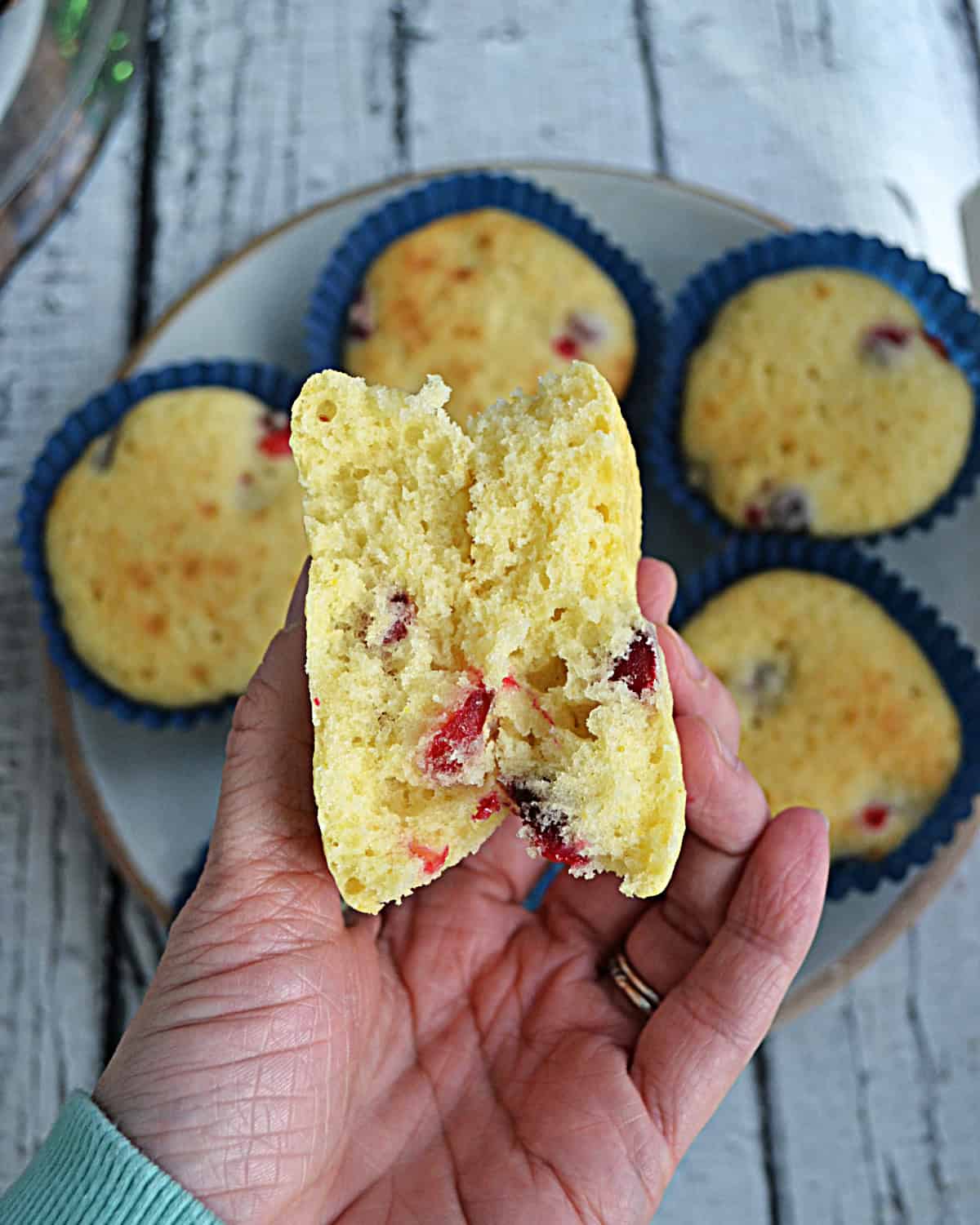 A hand holding a muffin split in half.