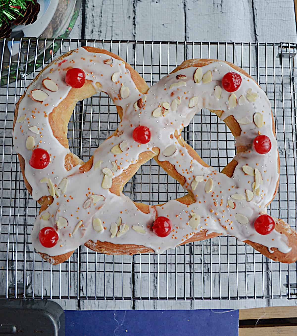 A large pretzel topped with glaze and cherries.