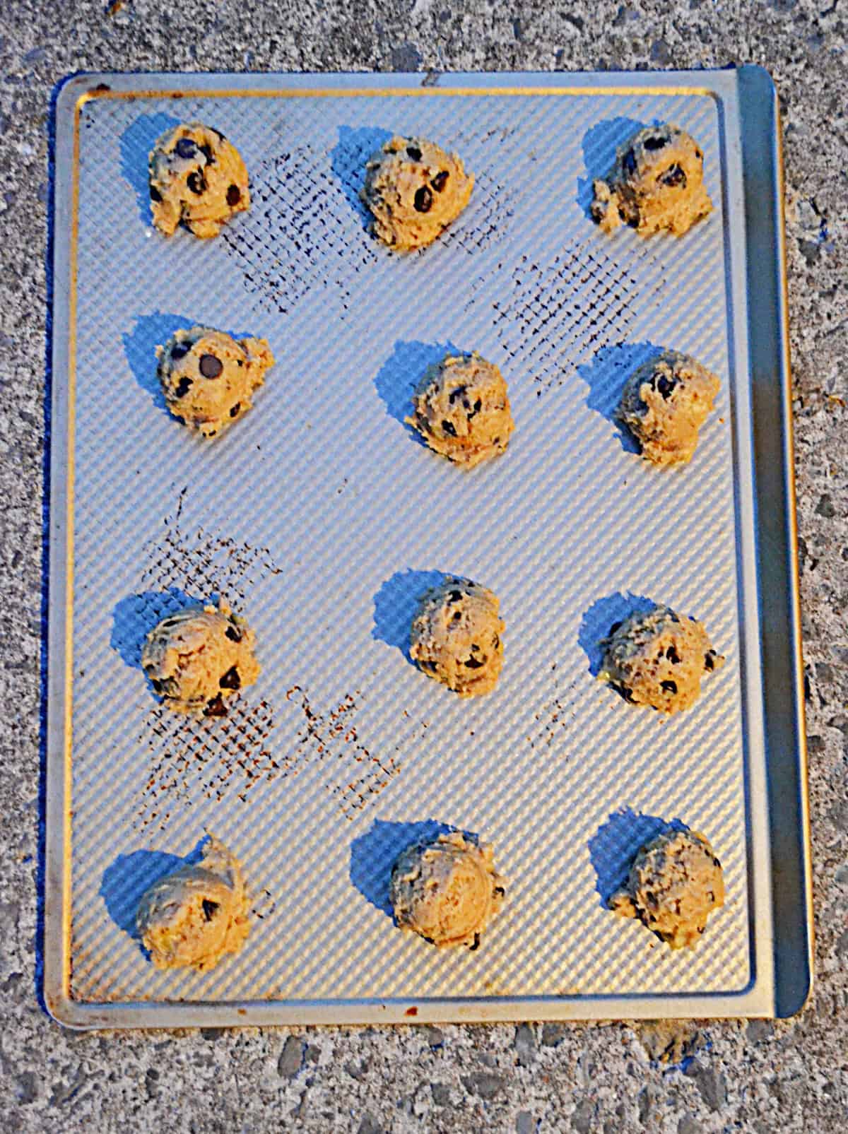 A baking tray with cookie dough balls on it.