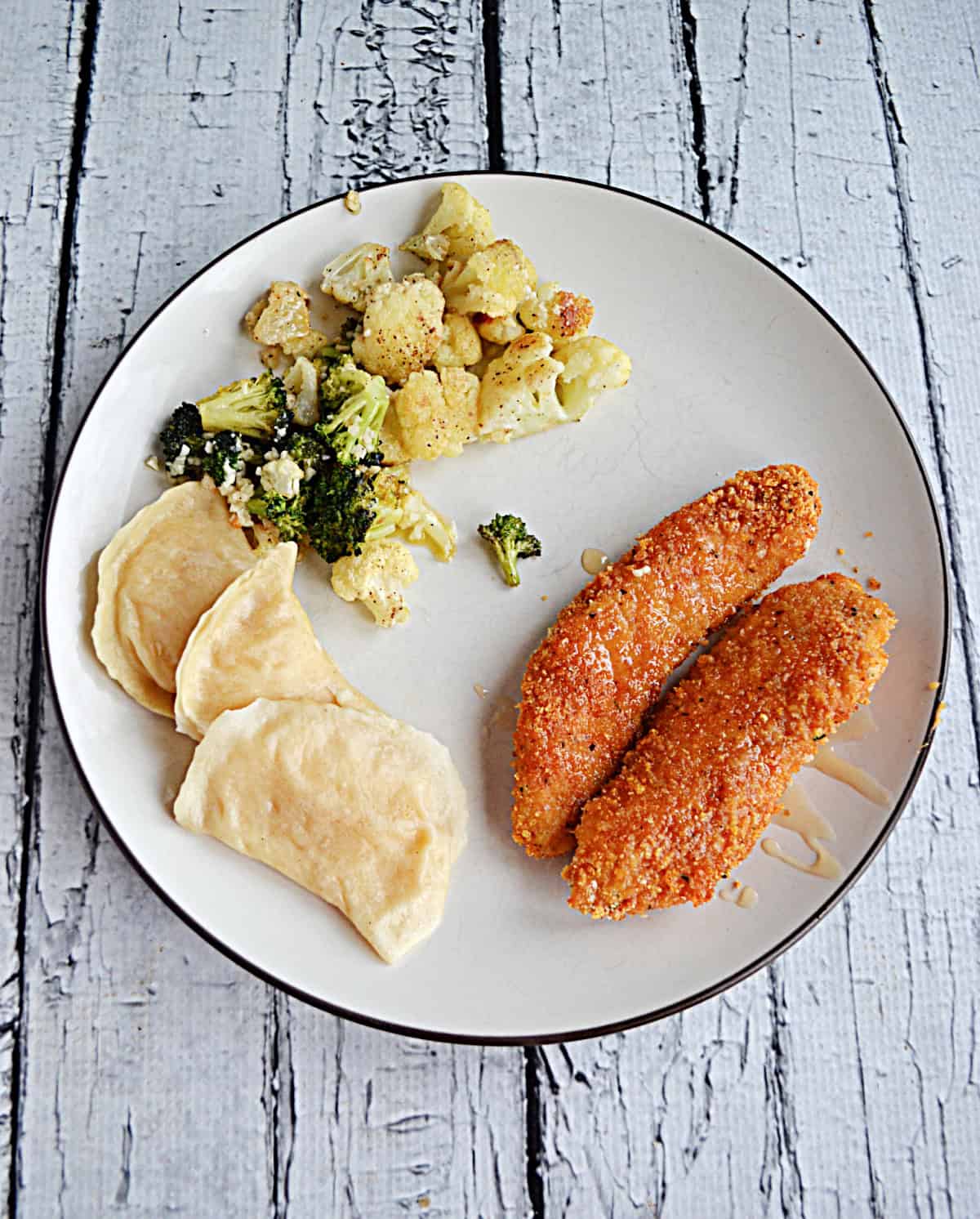 A plate of hot honey chicken, pierogi, and cauliflower.