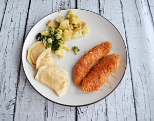 A plate with Hot Honey Chicken Strips and pirogies on it.