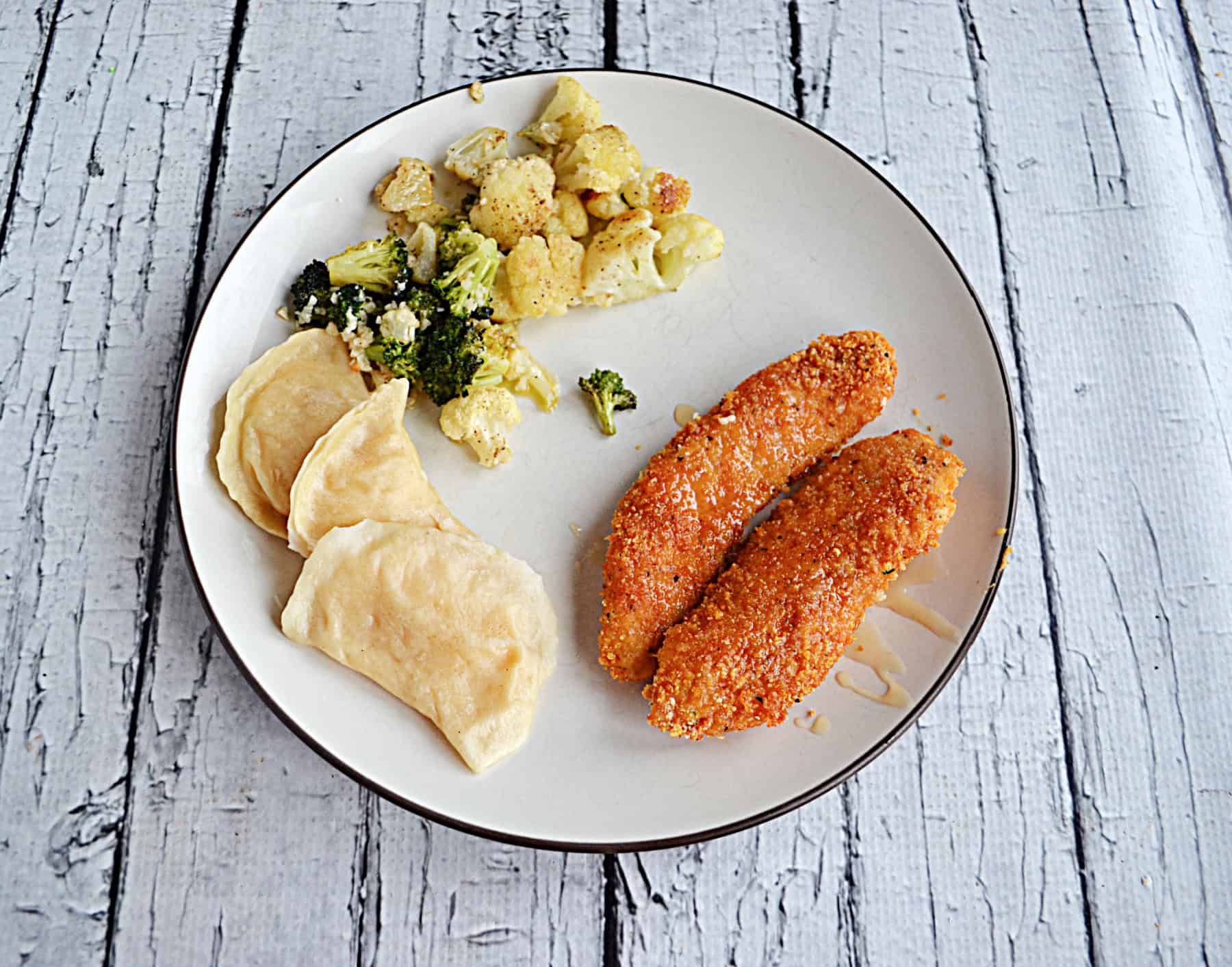 A plate with Hot Honey Chicken Strips and pirogies on it.