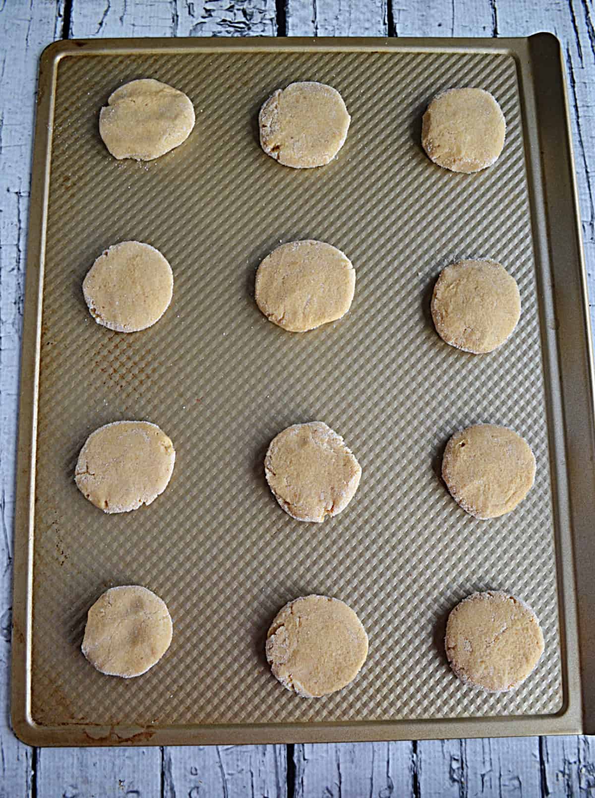 A baking sheet with cookie dough balls on it.