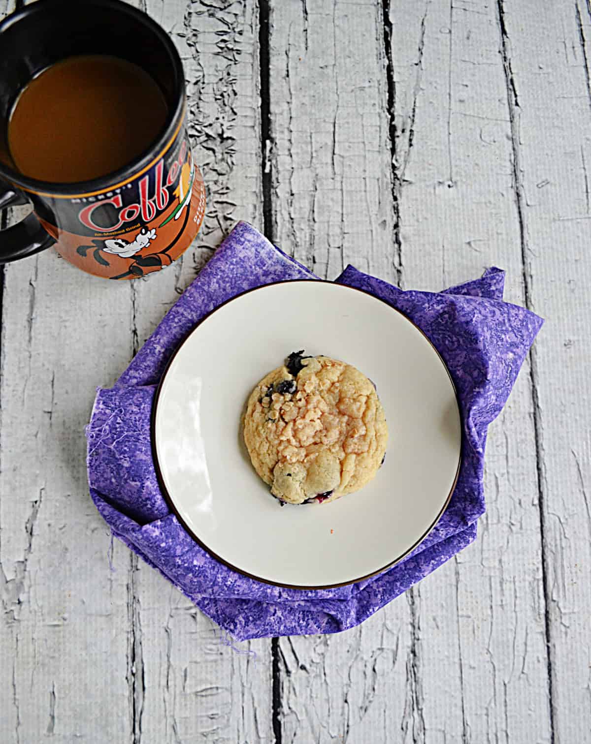 A top view of a plate with a cookie and a cup of coffee.