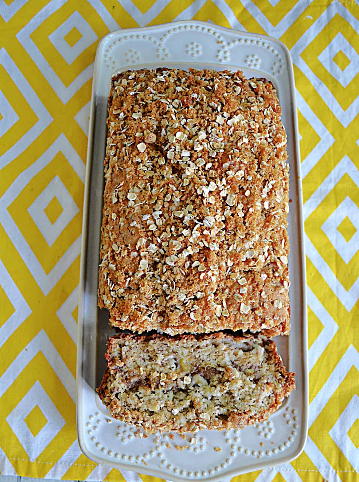 A platter with banana bread on it and a slice cut off and showing.