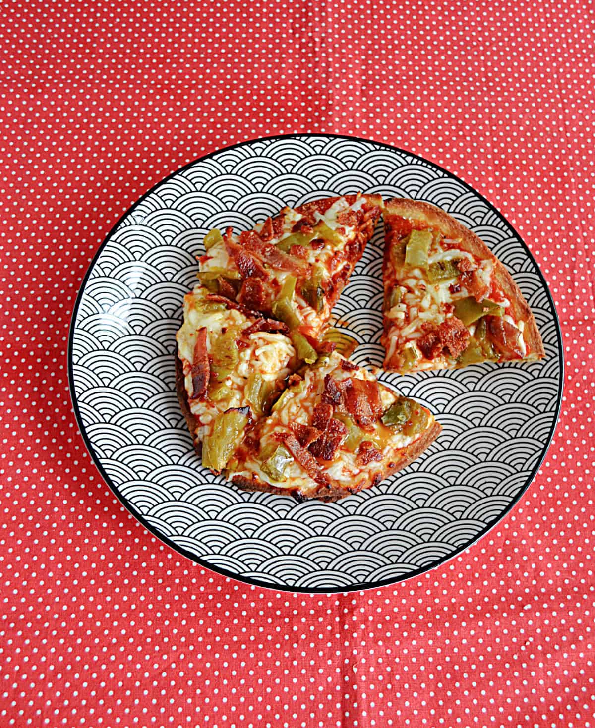 A Naan Pizza on a plate, cut into 4 pieces with one piece coming out.