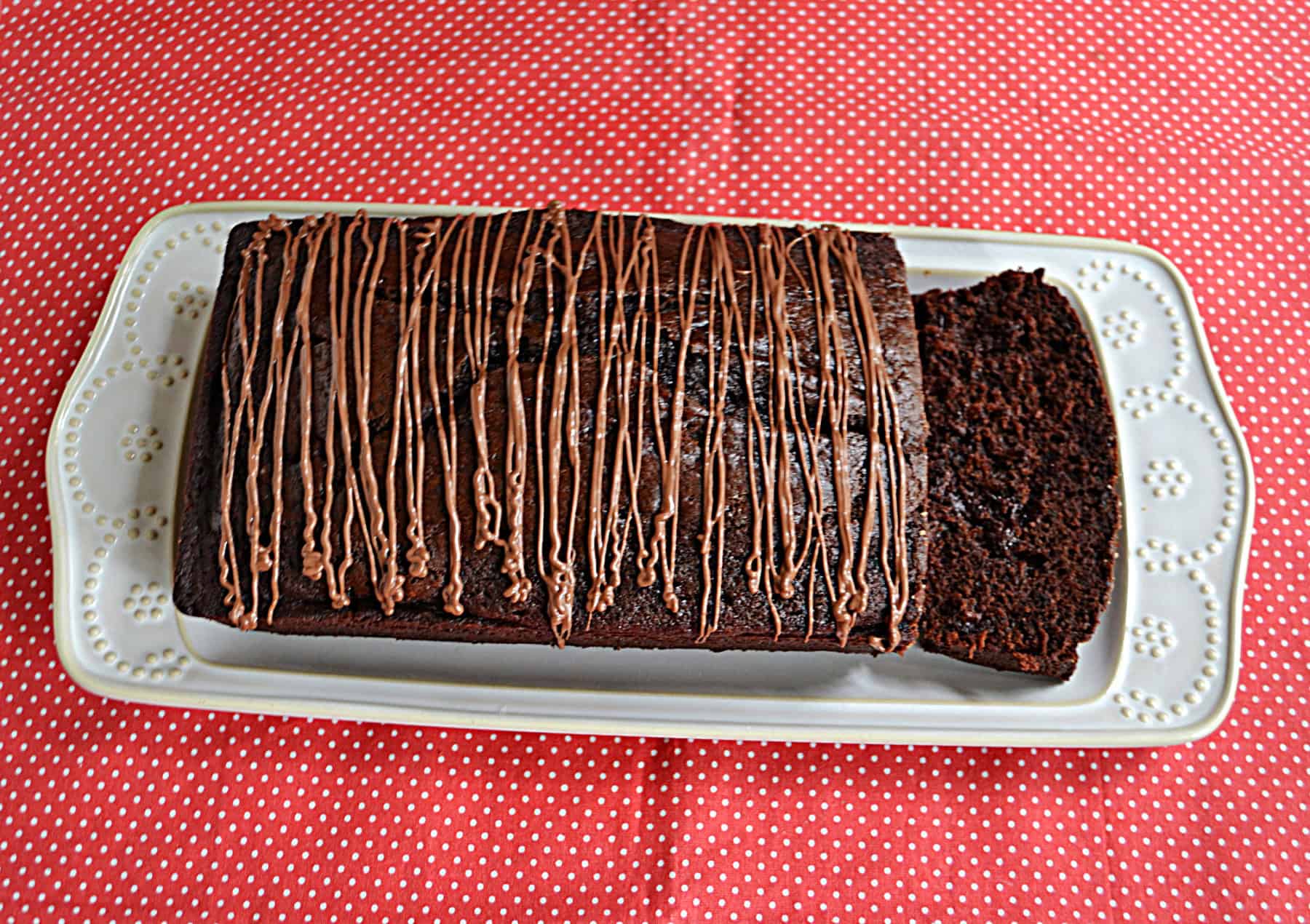 A white platter with chocolate bread and a chocolate drizzle on top.