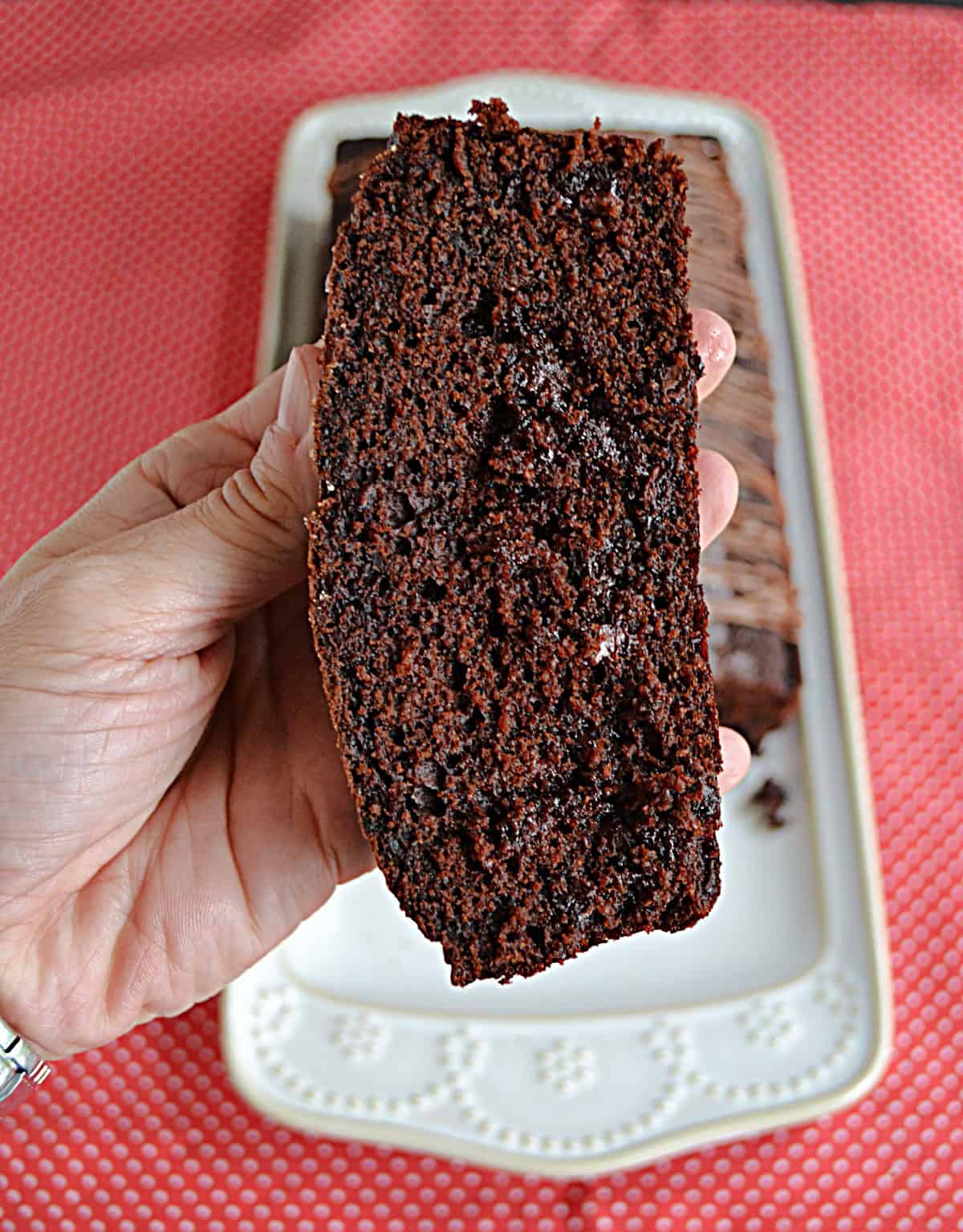 A hand holding a piece of double chocolate bread.