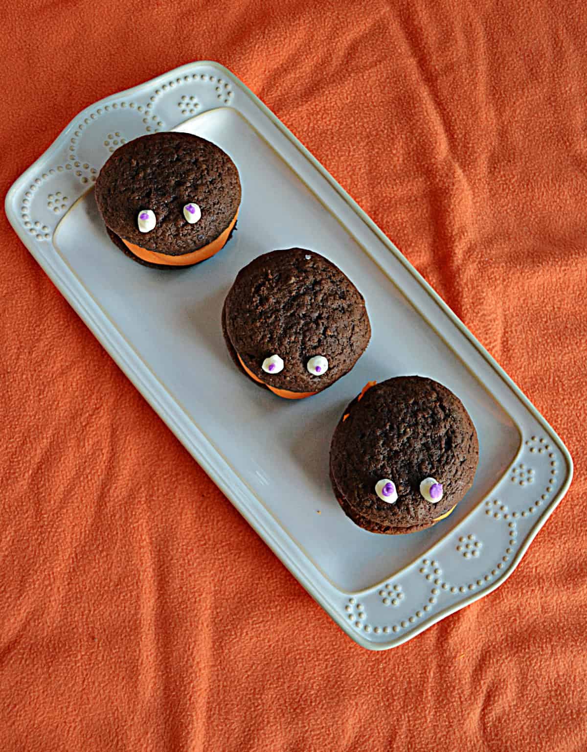 A platter with three chocolate whoopie pies with eyes on them.