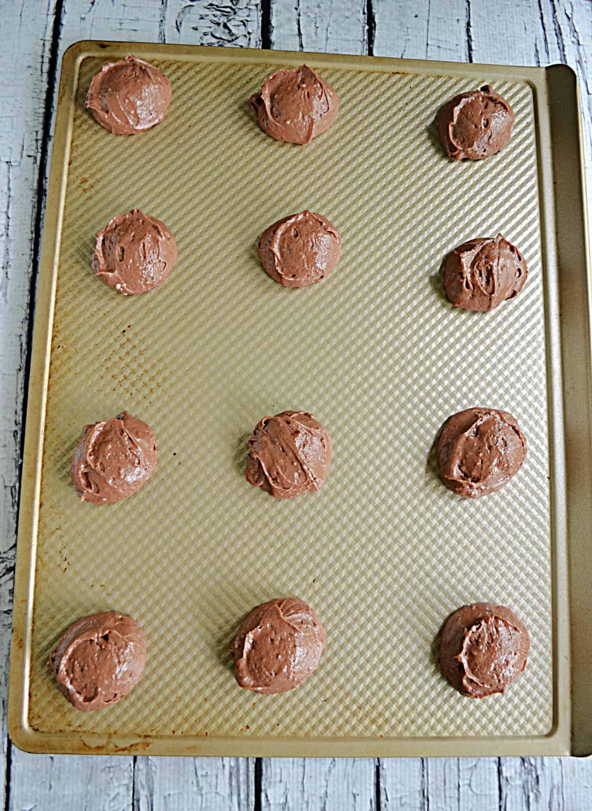 A baking sheet with 12 dough balls on it.