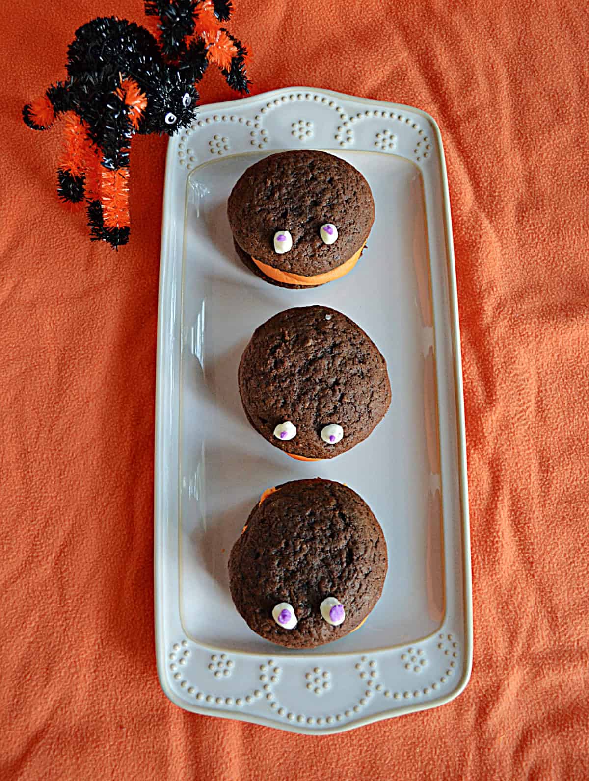 A platter with three chocolate whoopie pies with eyes on them.