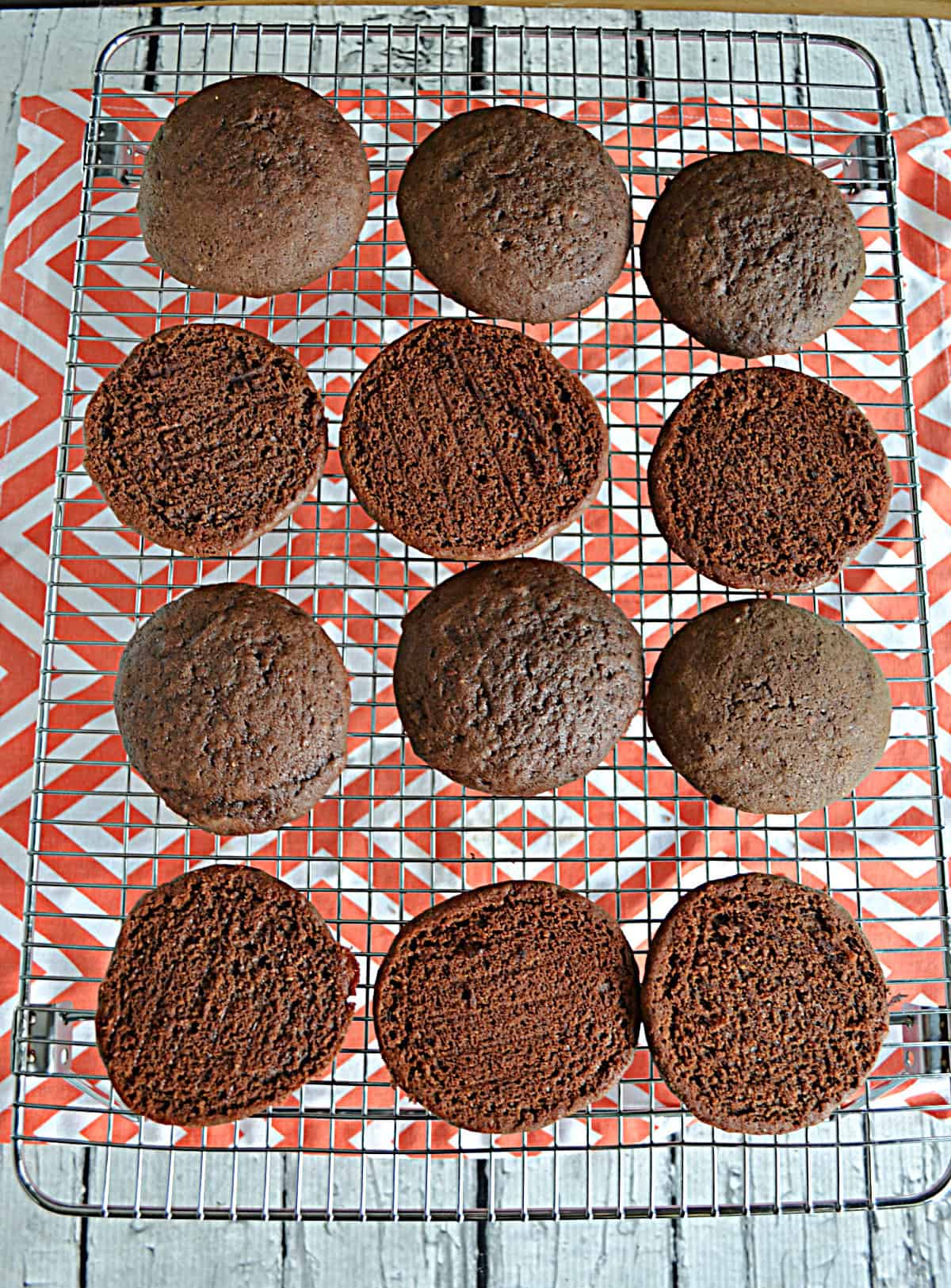 A cooling rack with 12 sandwich cookies on it.