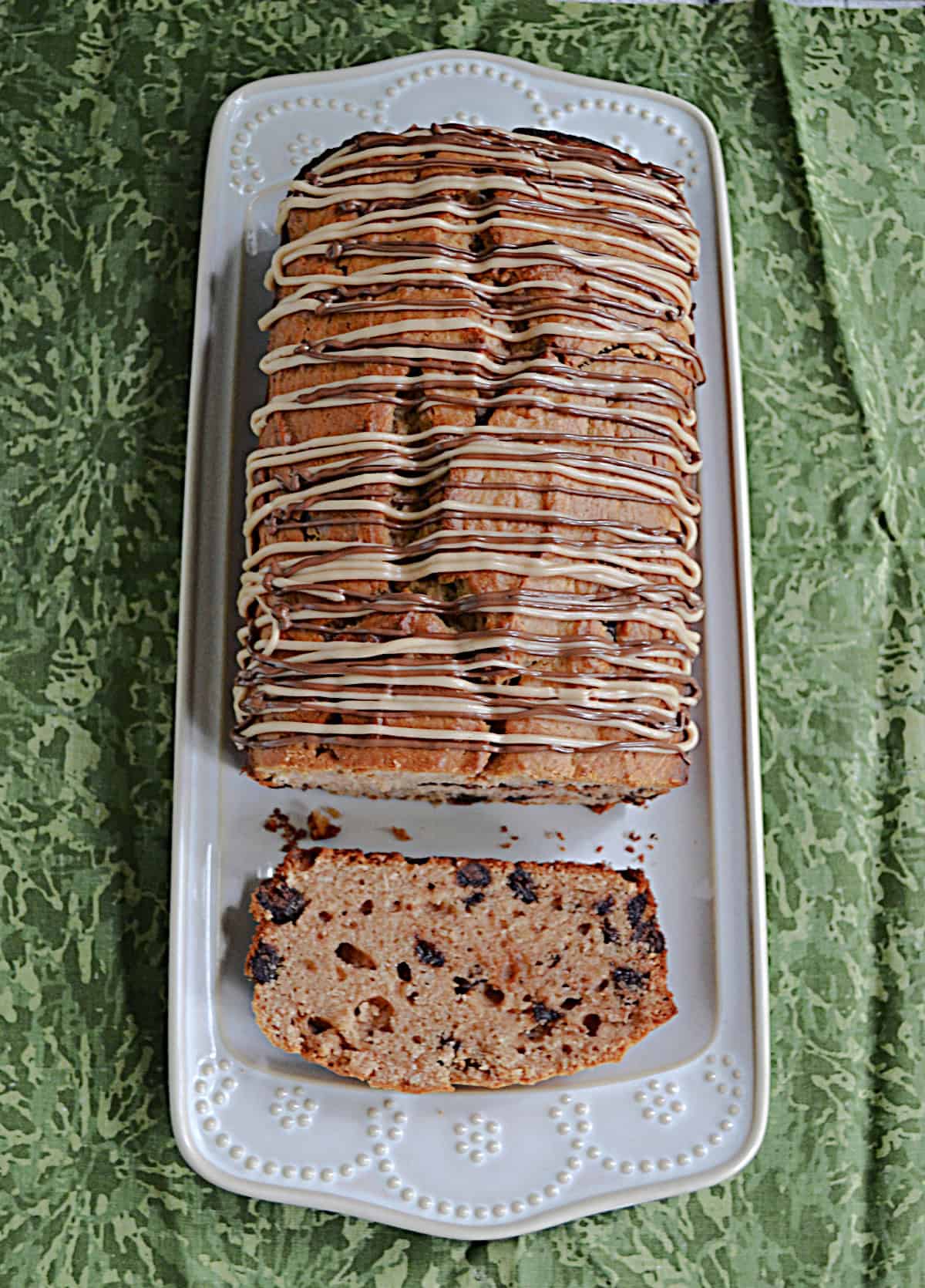 Peanut butter chocolate chip bread on a white platter with a slice of the bread showing.