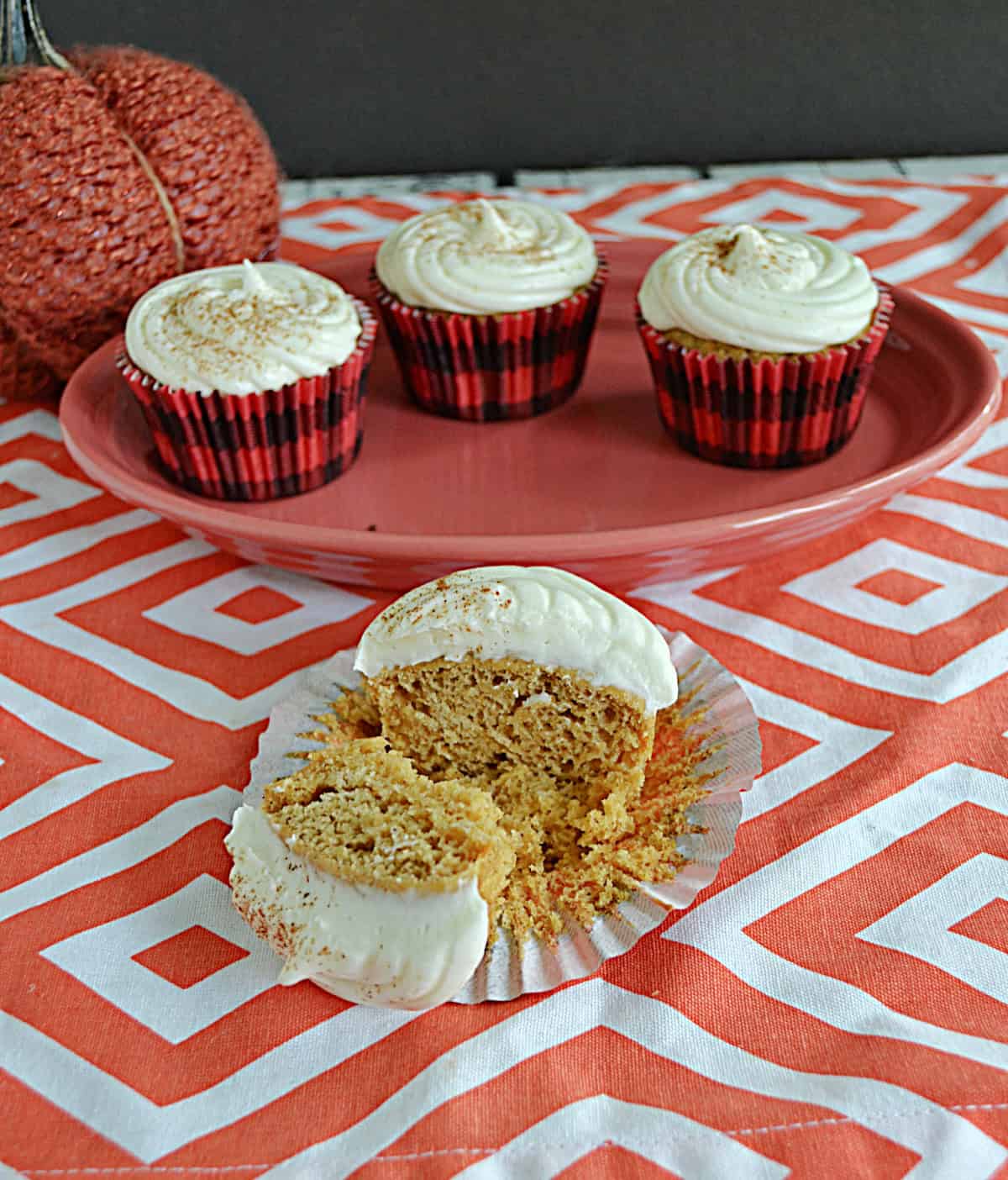 A close up of a cupcake with a bite taken out of it with a platter of cupcakes in the background.