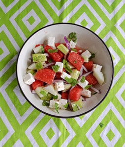 A bowl of watermelon chunks, feta cheese, mint, and cucumber.