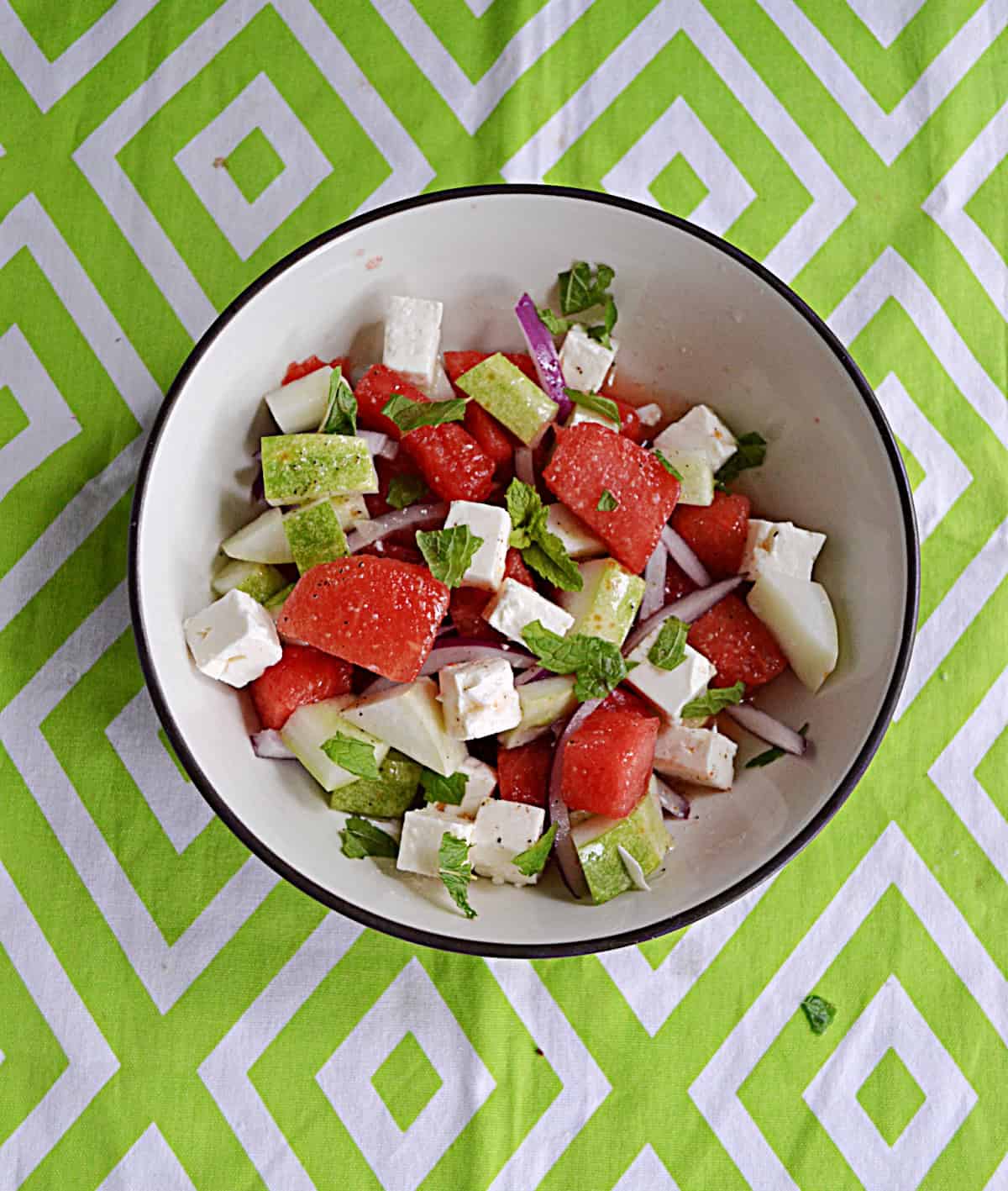 A bowl of watermelon chunks, feta cheese, mint, and cucumber.