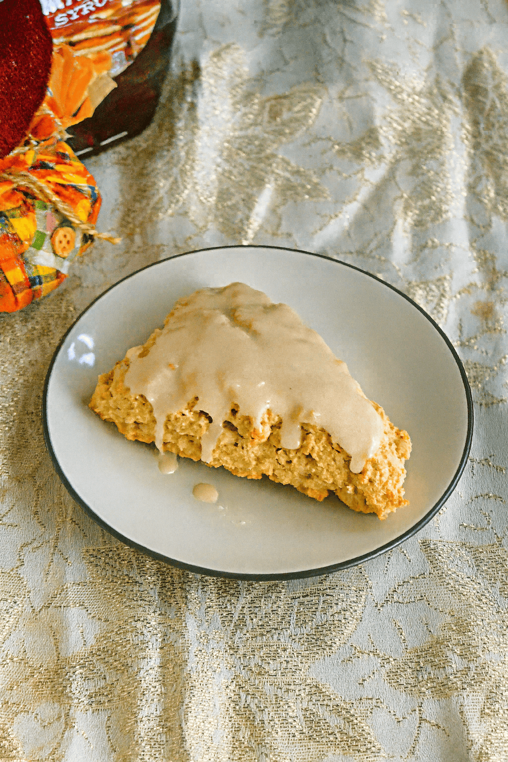 A plate with an iced maple scone on it.