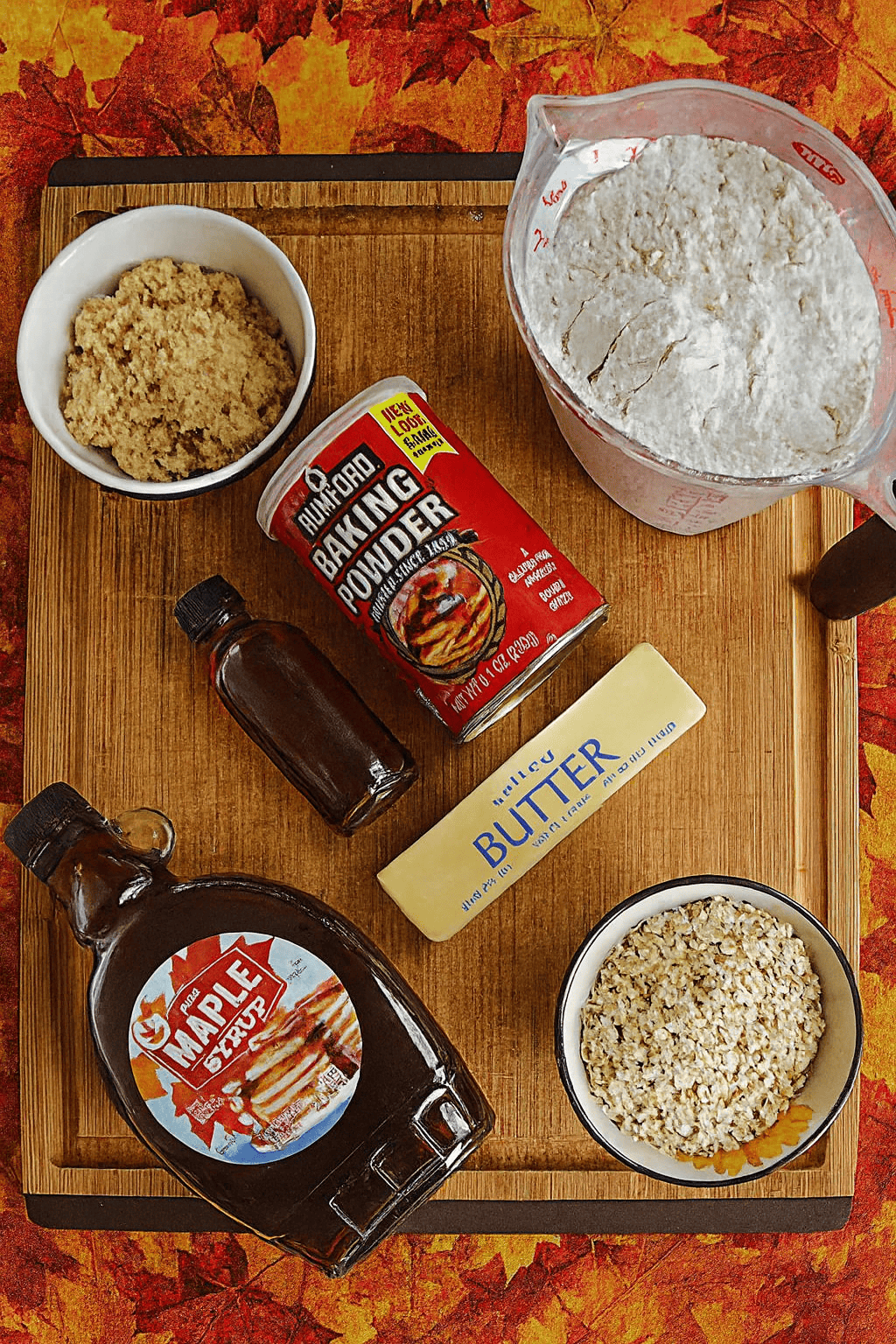 A cutting board with flour, brown sugar, oats, butter, and maple syrup on it.