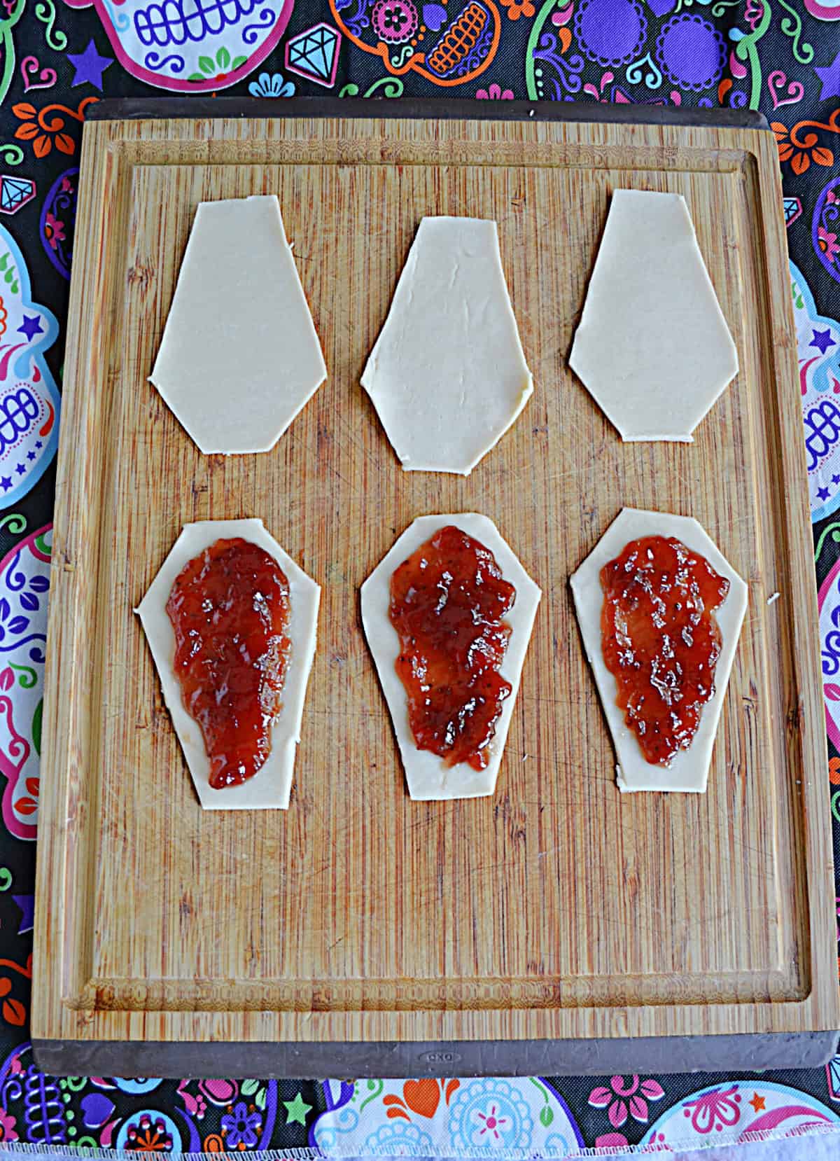 Three pastries with strawberry jam on them and three pastries without.