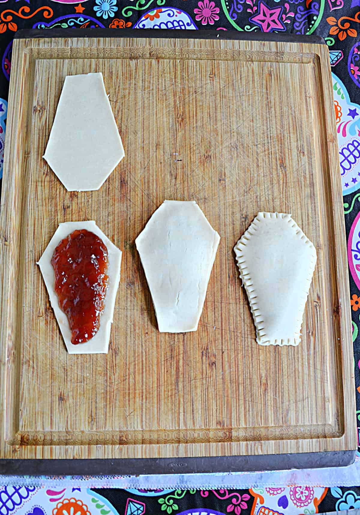 Coffin shaped pastries; two filled, one with filling on half of it and the top pastry waiting to be put on.
