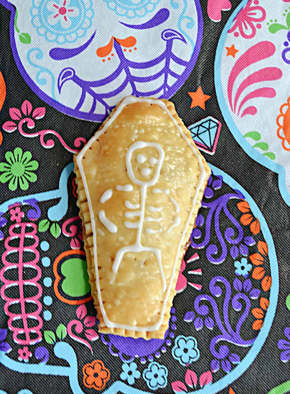 A close up of a coffin shaped pop tart with a skeleton on it.
