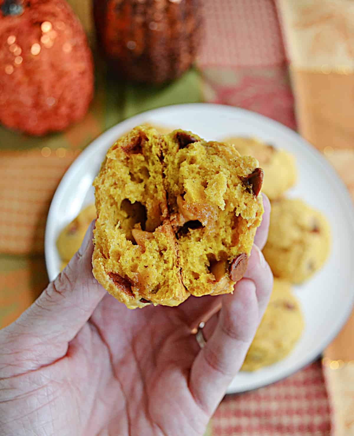 A hand holding a pumpkin cookie split in half.