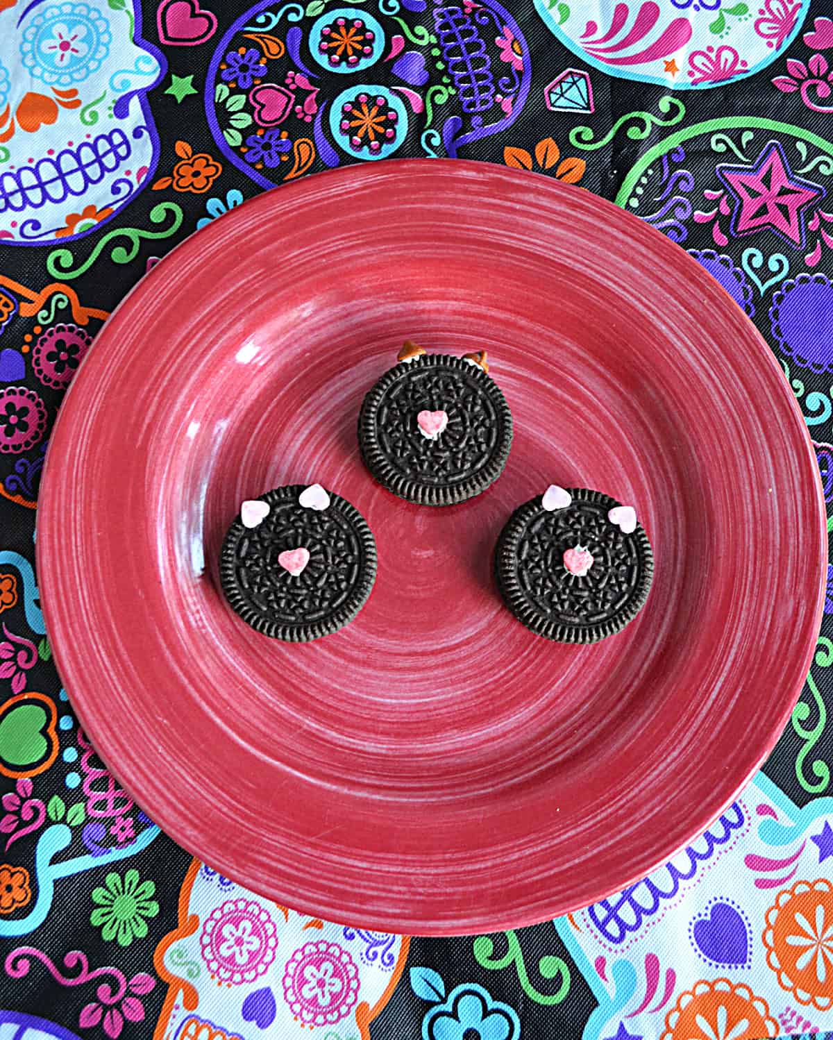A plate with three black cat cookies on it.