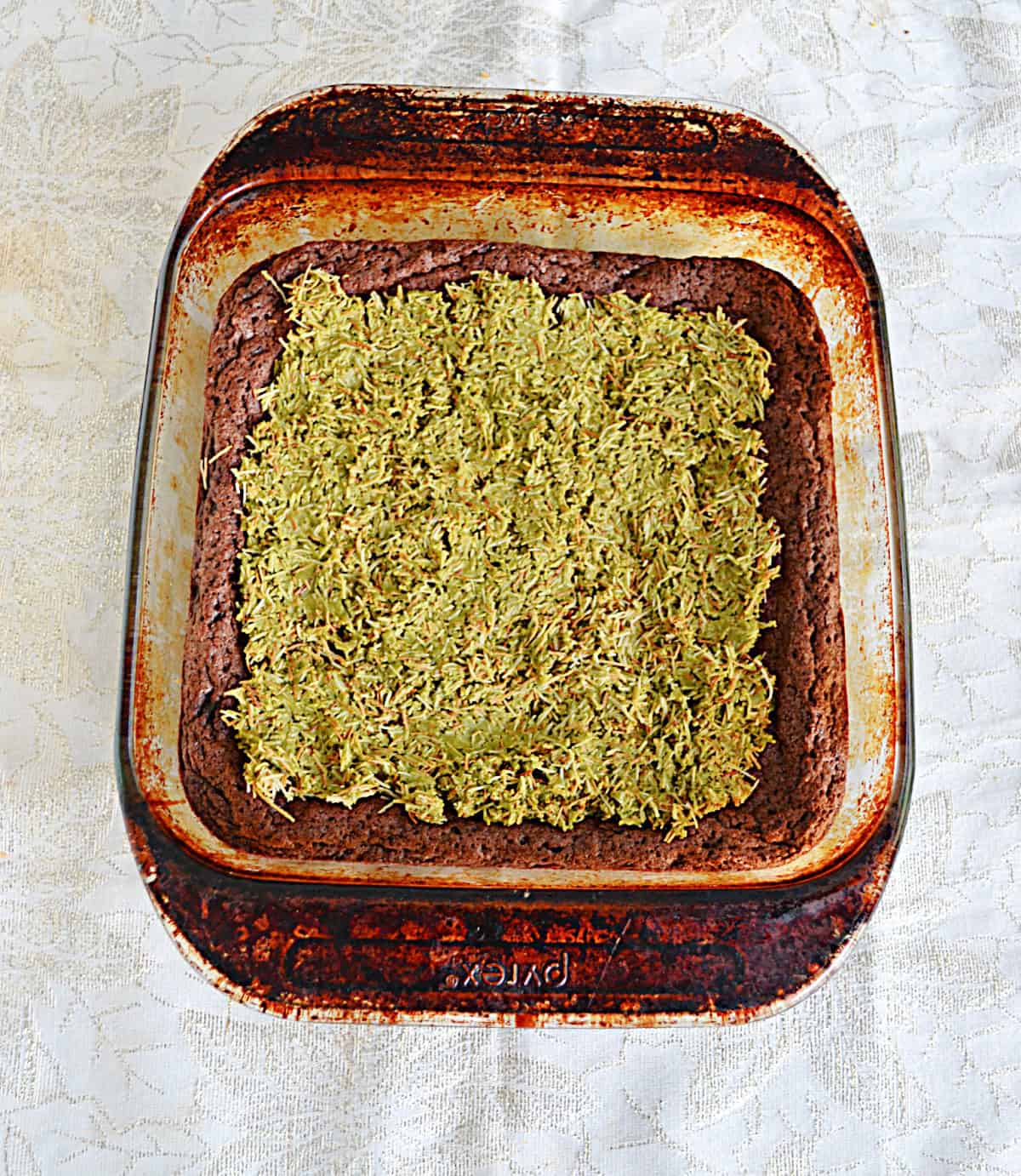 A pan of brownies with pistachio cream on top.
