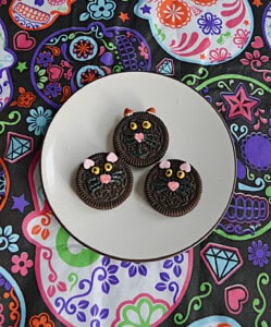 Three black cat face cookies on a plate.