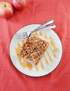 A plate with a slice of French toast, caramel drizzle, and two forks on it.