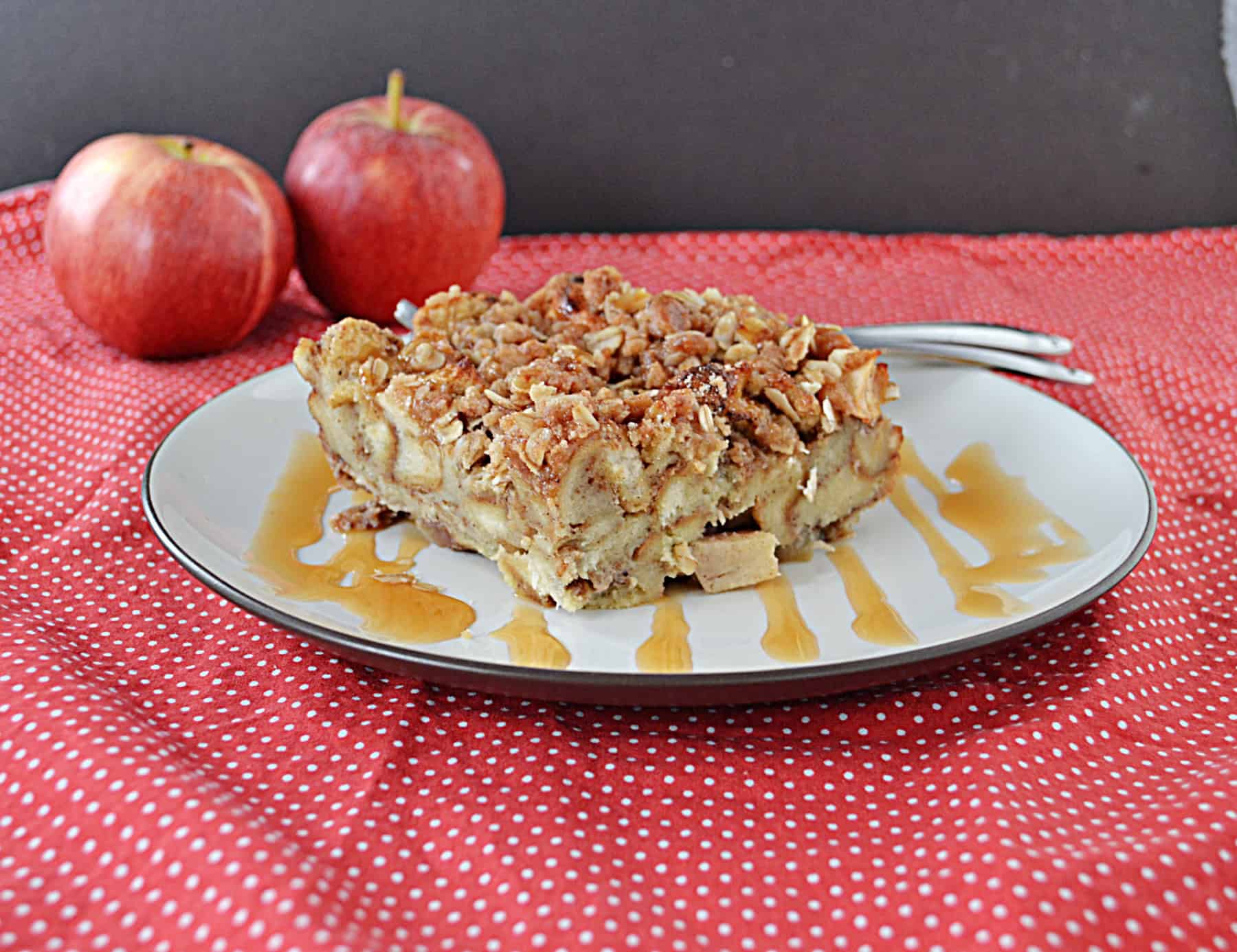 A plate of French Toast bake with a fork on the plate and apples in the background.
