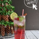 Pin Image: A glass with lime wedges, mint leaves, cranberries, and a straw by a Christmas tree with a list of ingredients.