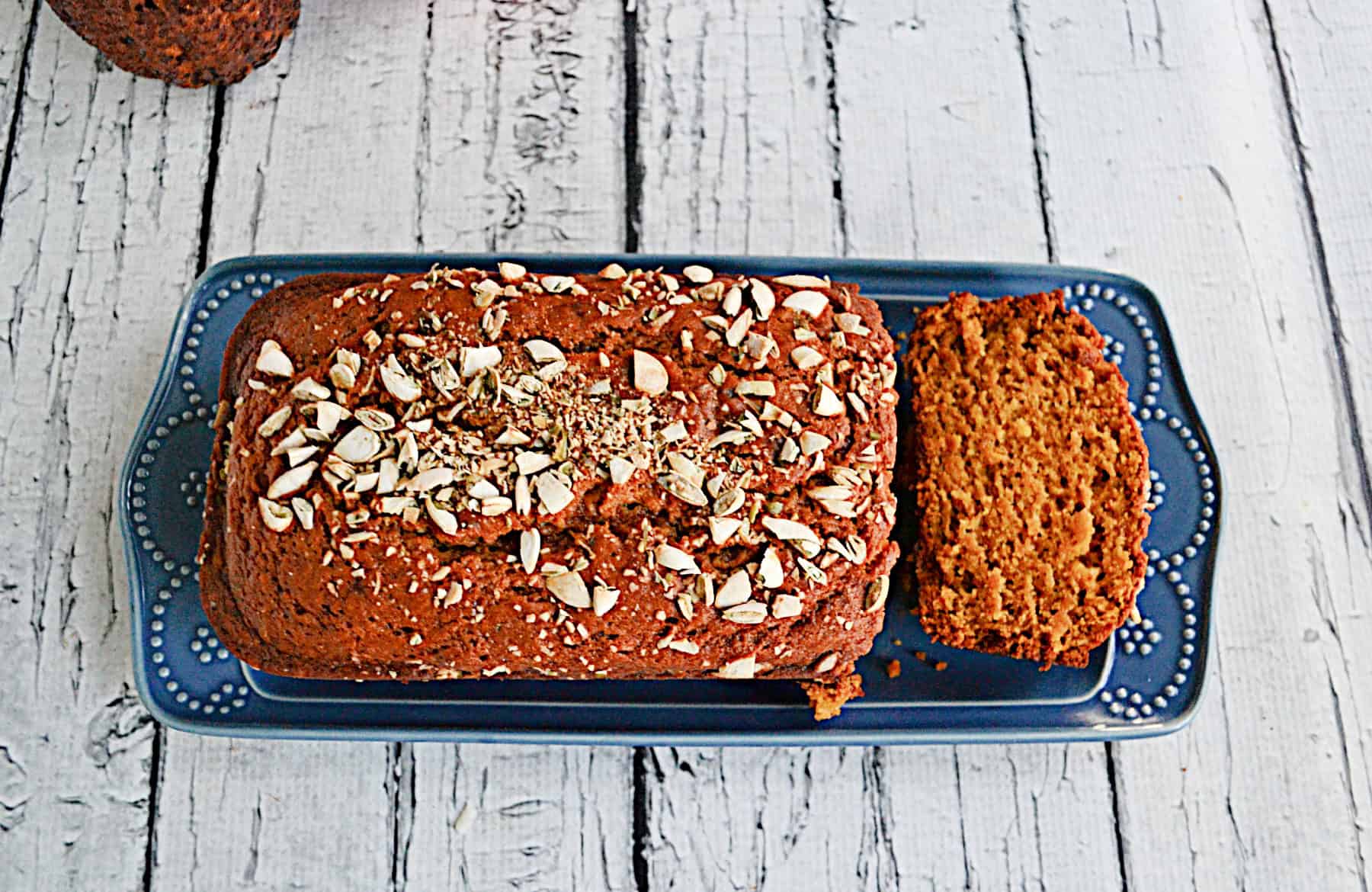 A top view of a load of pumpkin bread with pumpkin seeds on top.