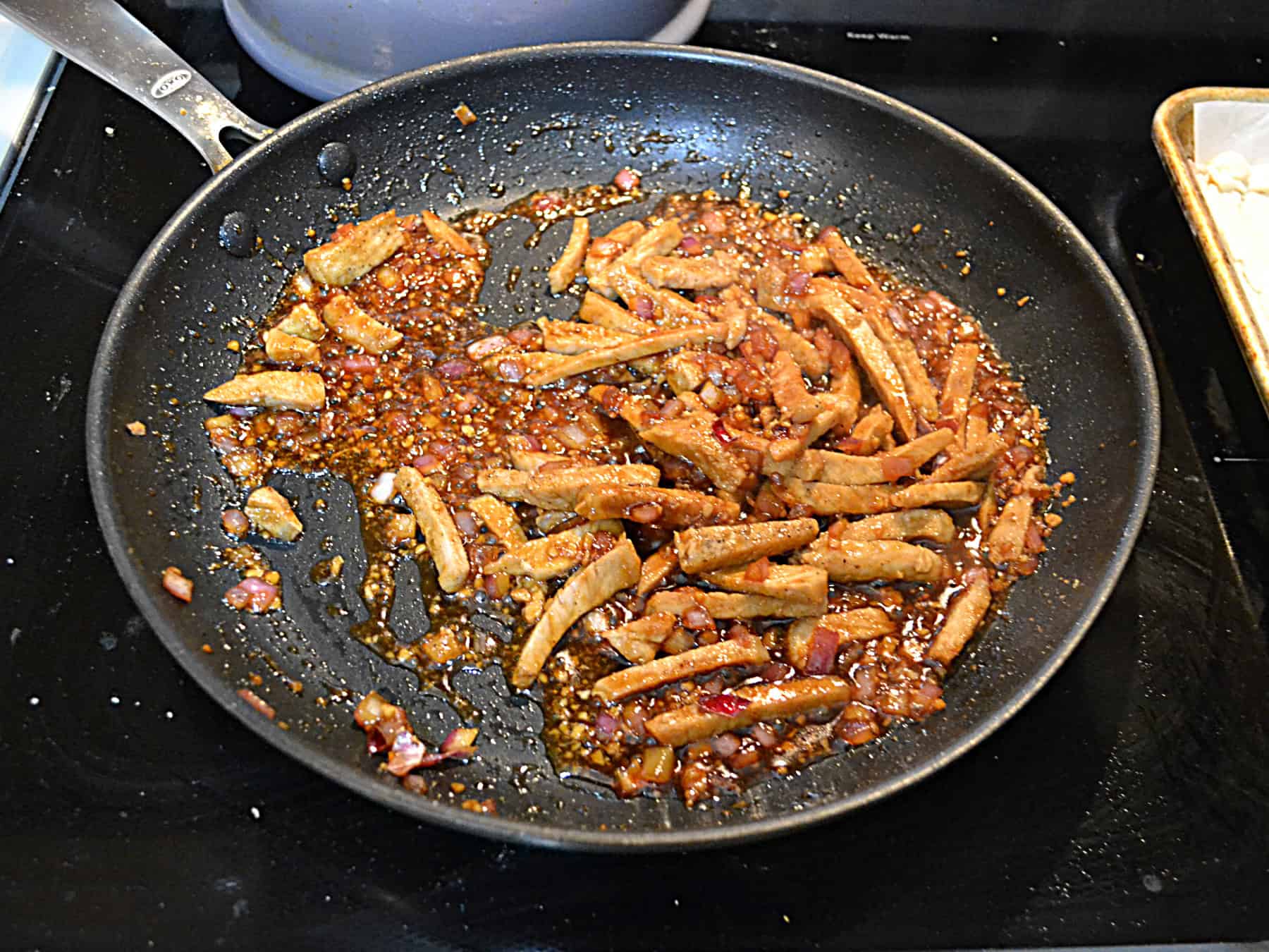 A saute pan with pork and sauce in it.