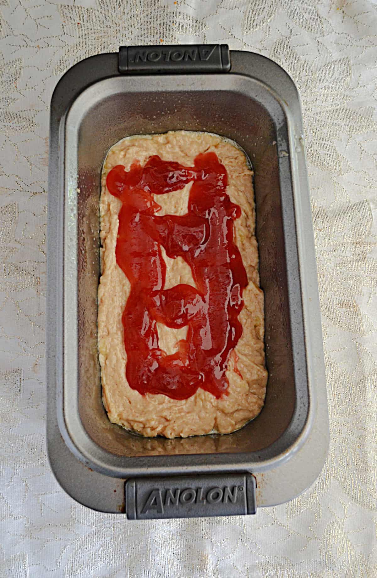 A pan of dough with strawberry jam on top.