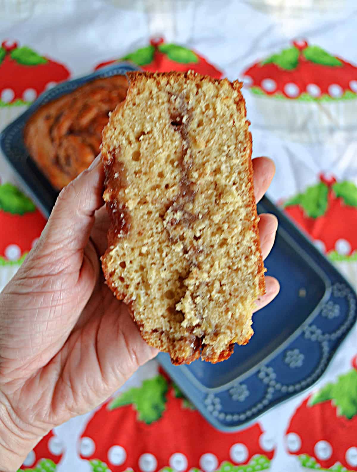 A hand holding a slice of bread with a ribbon of jam in the middle.